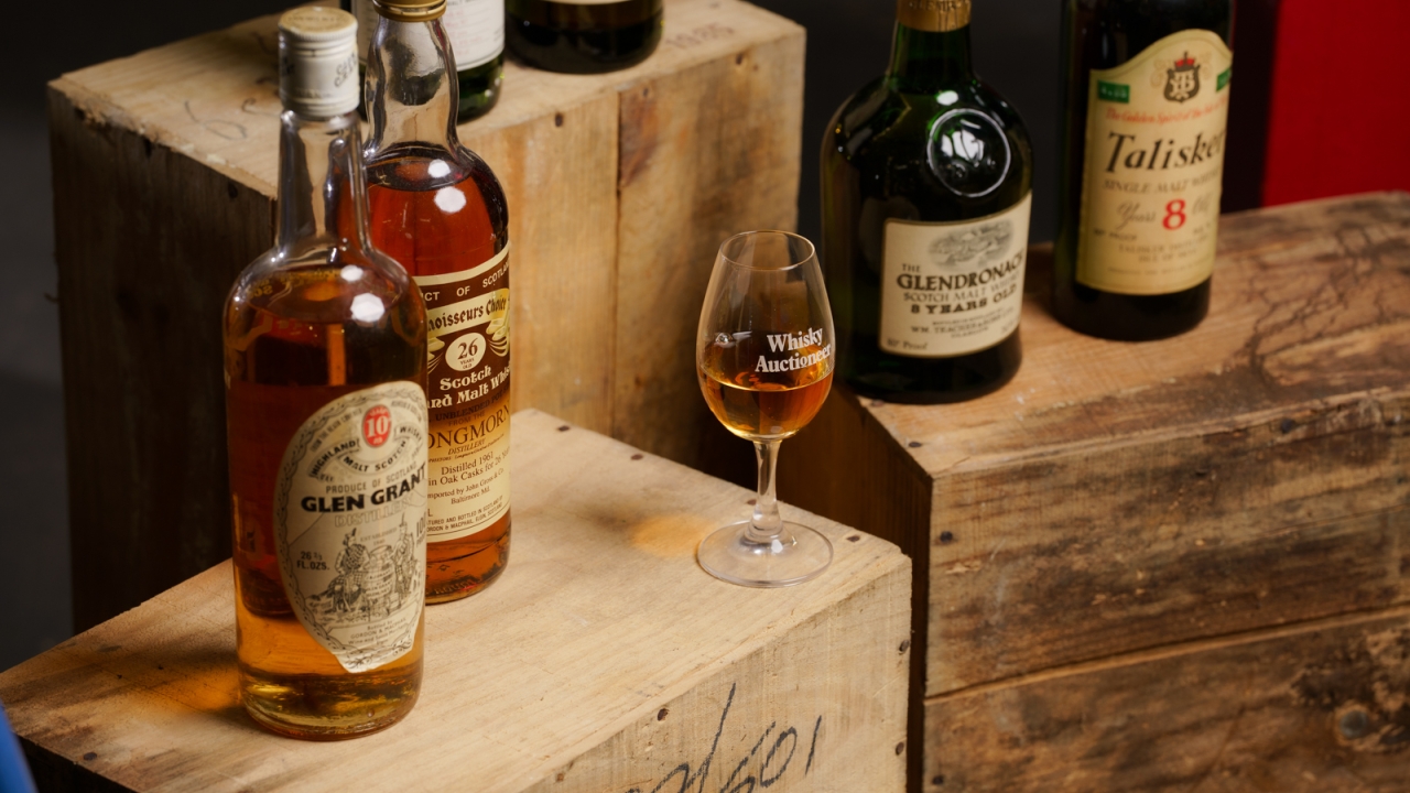 Whisky Auctioneer tasting glass surrounded by bottles